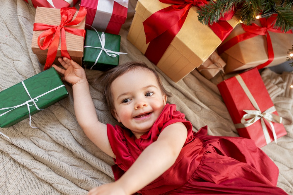christmas, holidays and childhood concept - happy baby girl with gifts at home. happy baby girl with christmas gifts at home