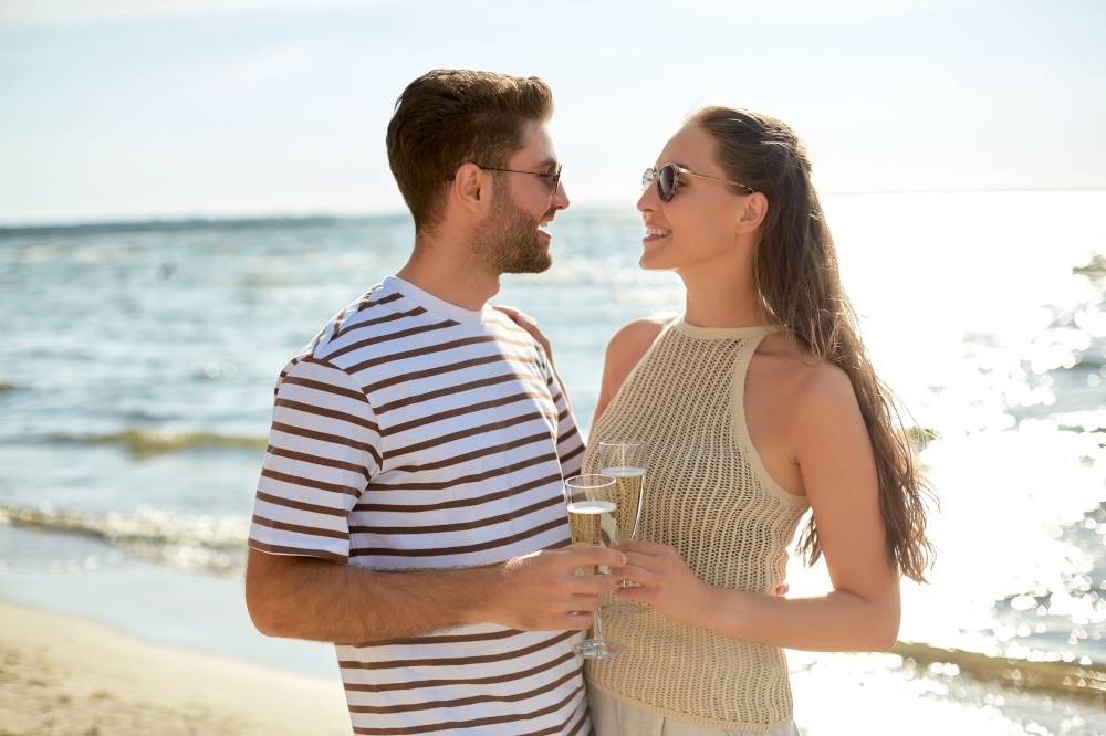 leisure, relationships and people concept - happy couple in sunglasses drinking champagne on summer beach. happy couple drinking champagne on summer beach