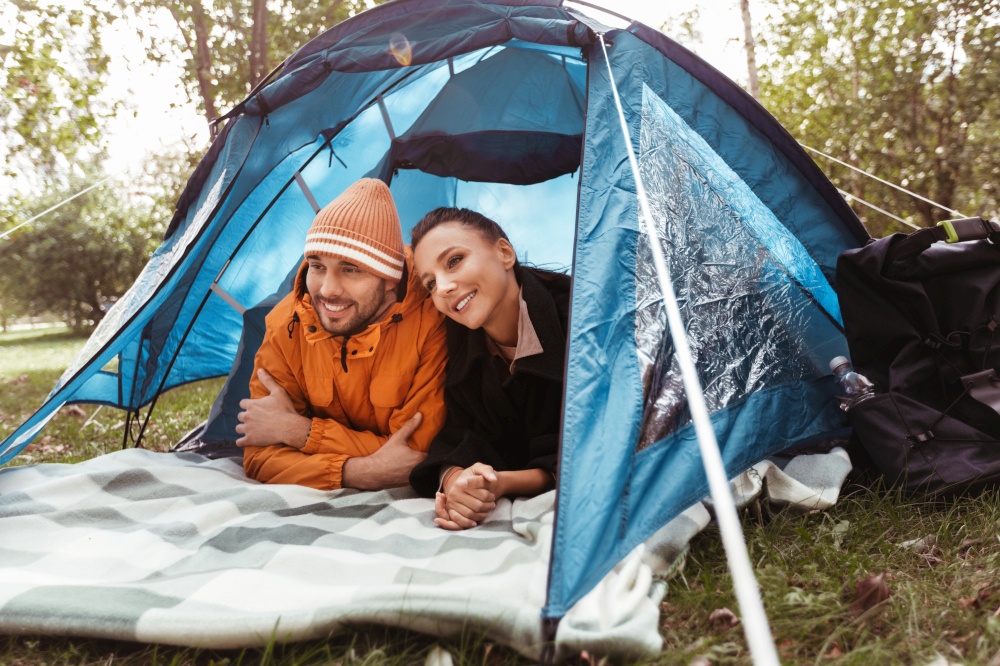 camping, tourism and travel concept - happy couple lying inside tent at campsite. happy couple lying inside tent at campsite