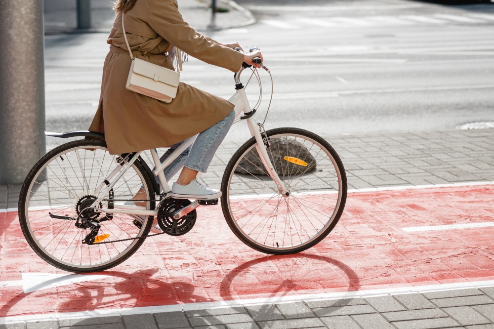 traffic, city transport and people concept - woman cycling along red bike lane or road for bicycle on street. woman cycling along red bike lane road in city