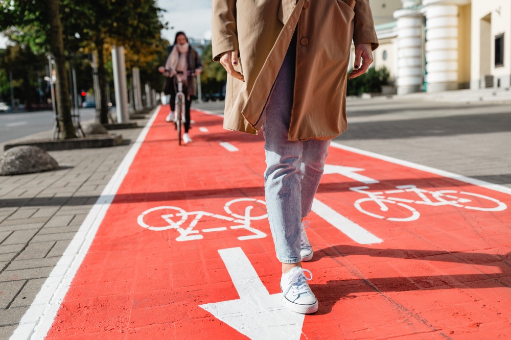 people, city and traffic concept - close up of woman&rsquo;s feet walking along separate bike lane or red road with signs only for bicycles on street. feet walking along bike lane or road for bicycles