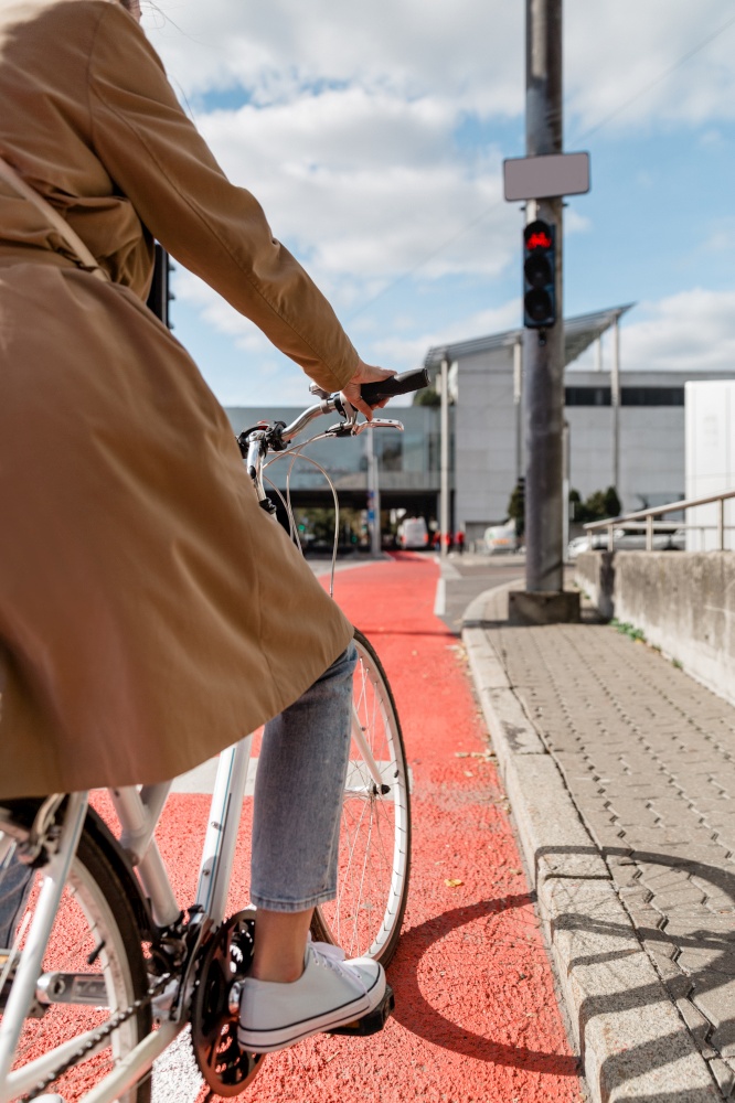 city transport and people concept - close up of woman with bicycle waiting for green traffic light signal on red bike lane in tallinn, estonia. woman on bicycle waiting for green traffic light