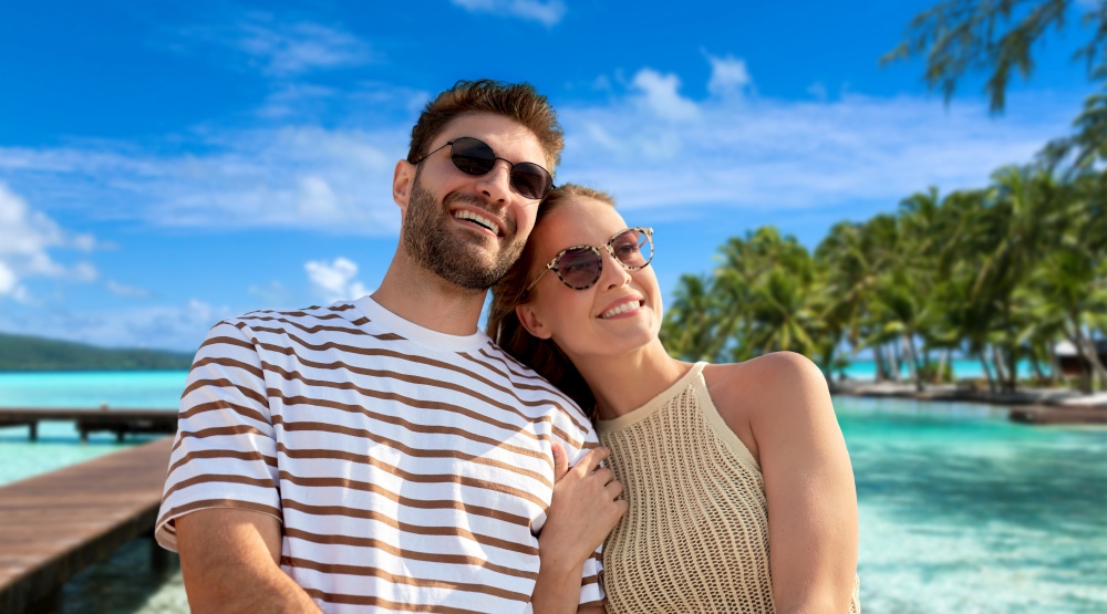 travel, tourism and people concept - happy couple in sunglasses over tropical beach background in french polynesia. happy couple over tropical beach background