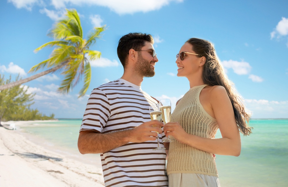 travel, tourism and people concept - happy couple in sunglasses drinking champagne over tropical beach background in french polynesia. happy couple drinking champagne on tropical beach