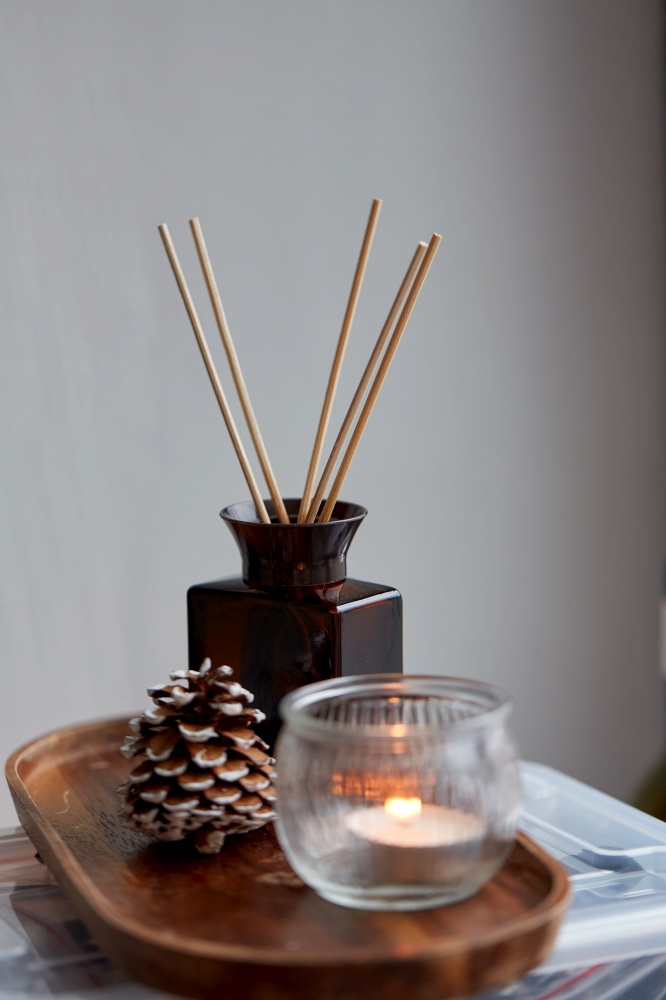 christmas, winter holidays and decoration concept - close up of aroma reed diffuser, pine cone and candle at home. aroma reed diffuser, pine cone and candle at home