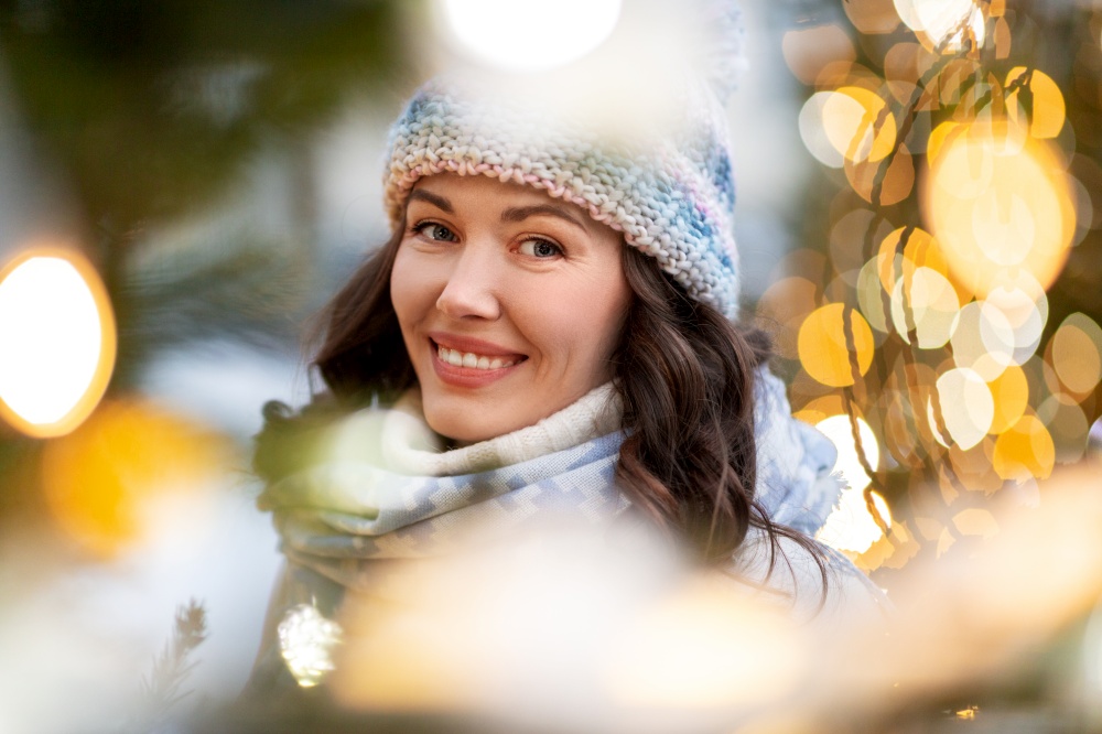 winter holidays and people concept - portrait of happy smiling young woman in christmas lights. portrait of happy young woman in christmas lights