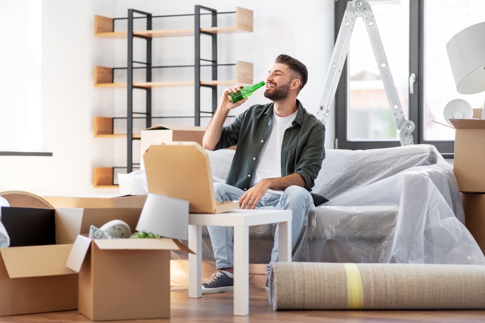 moving, people and real estate concept - happy smiling man with box of pizza and beer bottle at new home. man with box of pizza and beer bottle at new home