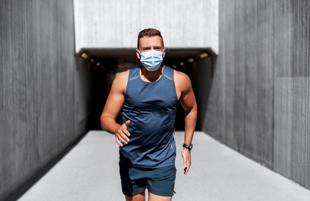 fitness, sport and health concept - young man in medical mask running outdoors. young man in medical mask running outdoors