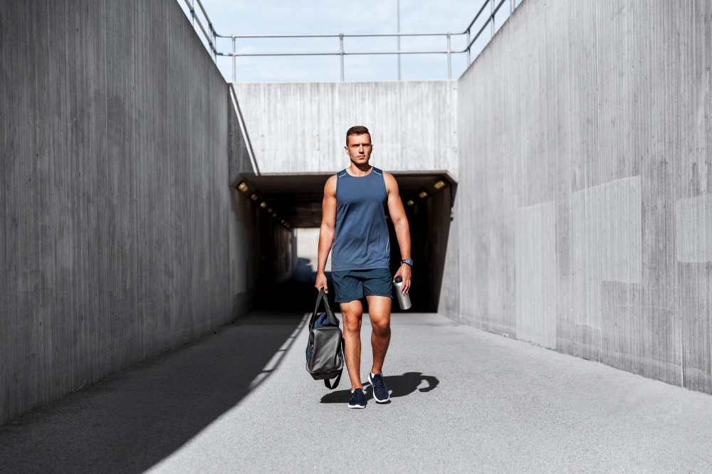fitness, sport and people concept - sportsman with bag and bottle of water walking outdoors. sportsman with bag and bottle walking outdoors