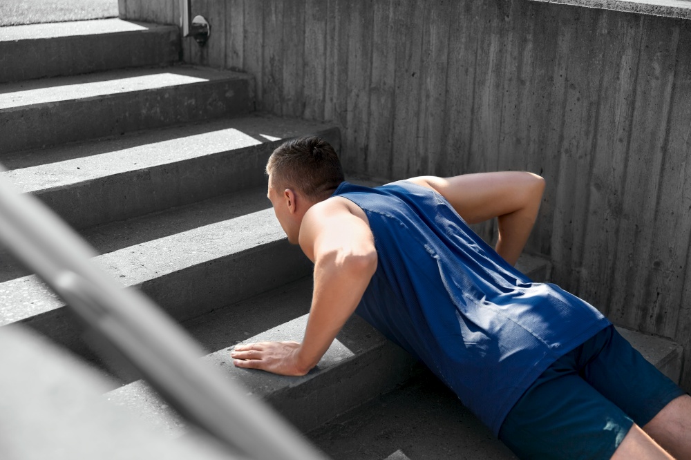 fitness, sport and training concept - young man doing push ups on stairs. young man doing push ups on stairs