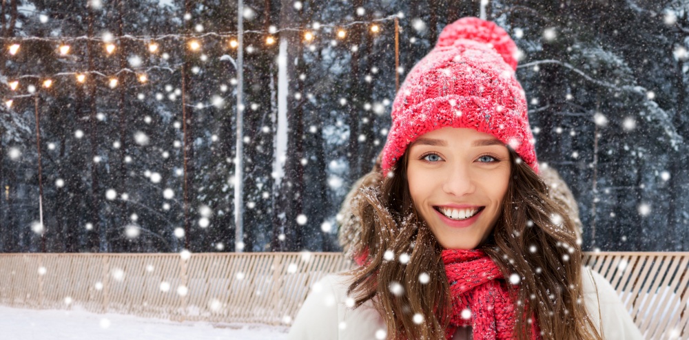 winter holidays, christmas and leisure concept - portrait of happy smiling teenage girl or young woman over skating rink on background. happy teenage girl in winter over skating rink