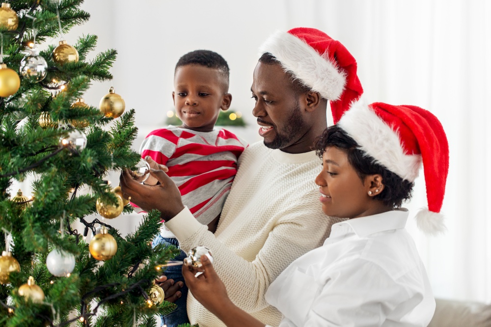 family, winter holidays and people concept - happy african american mother, father and baby son decorating christmas tree at home on. happy family decorating christmas tree at home