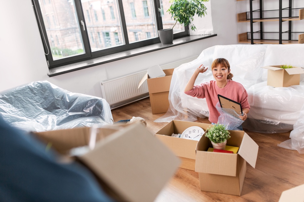 moving, people and real estate concept - happy smiling woman with boxes at new home throwing packing peanuts. woman unpacking boxes and moving to new home