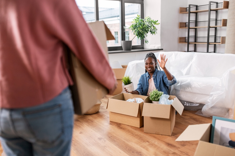 moving, people and real estate concept - happy smiling woman unpacking boxes at new home and waving hand. woman unpacking boxes and moving to new home