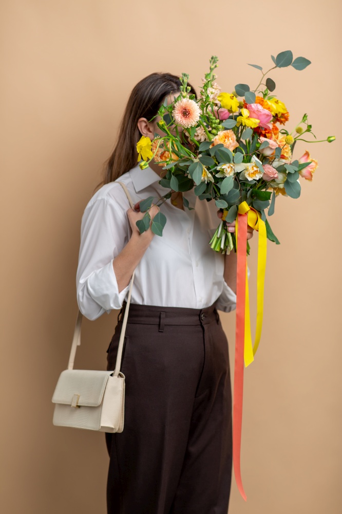 people and floral design concept - portrait of woman with bunch of flowers over beige background. portrait of woman with bunch of flowers