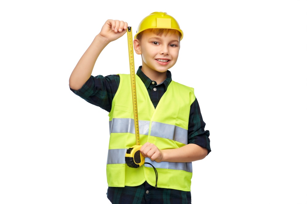 building, construction and profession concept - happy smiling little boy in protective helmet and safety vest with ruler over white background. boy in construction helmet and vest with ruler