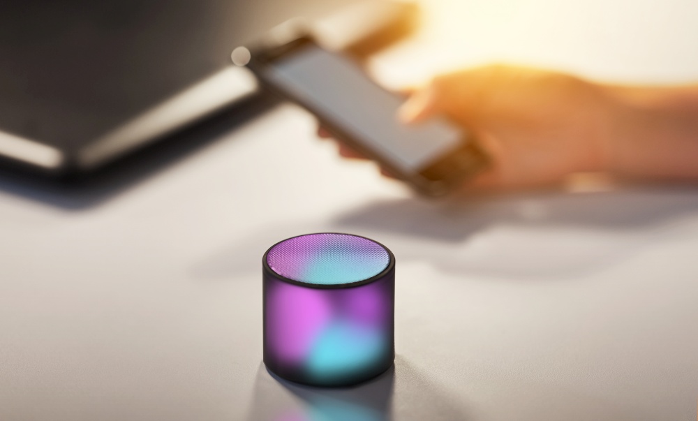 technology concept - glowing smart speaker on table at office. glowing smart speaker on table at office