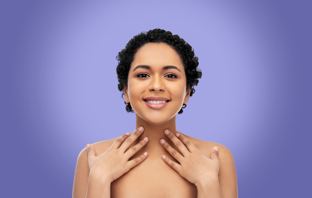 beauty and people concept - portrait of happy smiling young african american woman with bare shoulders over violet background. portrait of young african american woman on violet