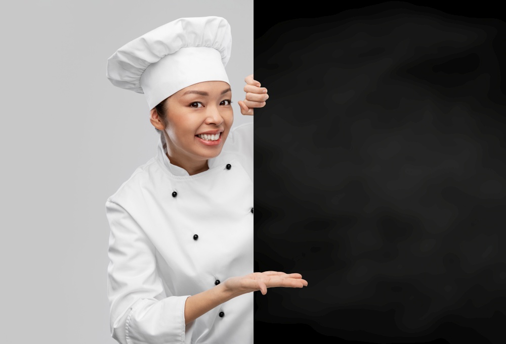 cooking, advertisement and culinary concept - happy smiling female chef with black chalkboard over grey background. smiling female chef with black chalkboard