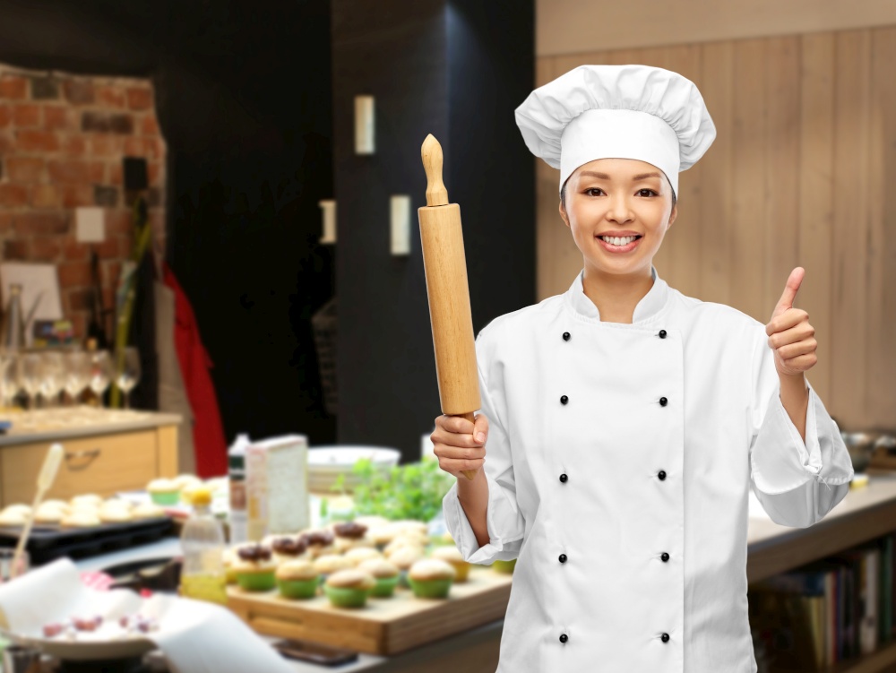 cooking, culinary and people concept - happy smiling female chef or baker with rolling pin showing thumbs up over grey background. smiling female chef or baker with rolling pin