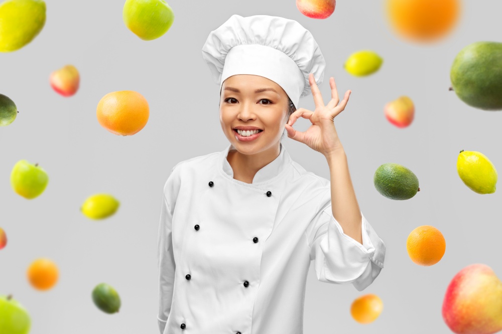 food cooking, vegetarian and culinary concept - happy smiling female chef showing ok hand sign over fruits on grey background. happy smiling female chef showing ok hand sign