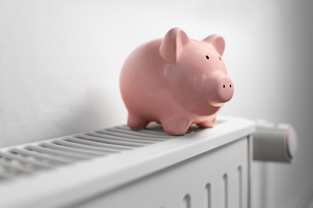 heating, energy crisis and consumption concept - piggy bank on radiator at home. piggy bank on radiator at home