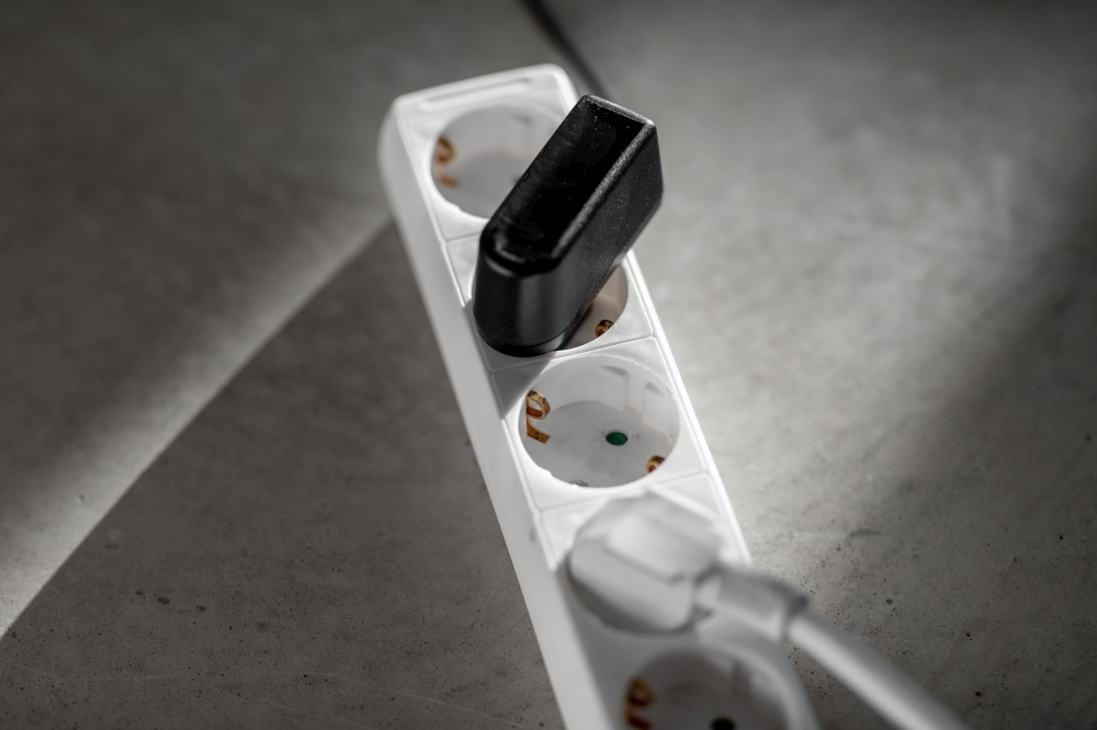 electricity, energy and power consumption concept - close up of socket with plugs and charger on concrete floor. close up of socket with plugs and charger on floor