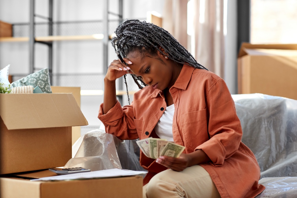 moving, finances and real estate concept - stressed woman with money, bills and calculator at new home. woman moving to new home and counting money