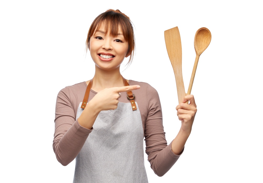 cooking, culinary and people concept - happy smiling female chef in apron with wooden spoon over white background. happy woman in apron with wooden spoon and spatula
