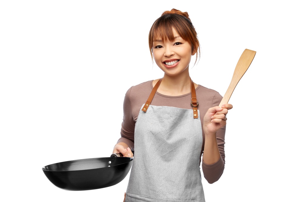 cooking, culinary and people concept - happy smiling female chef in apron with frying pan and spatula over white background. happy smiling female chef with frying pan