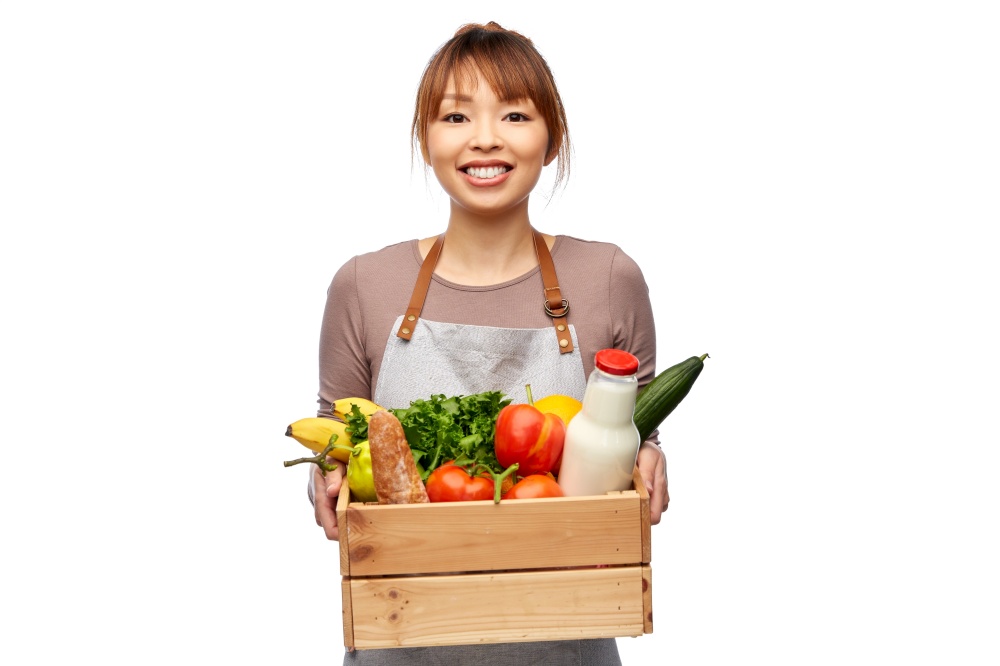 cooking, culinary and people concept - happy smiling female chef in apron with food in wooden box over white background. happy smiling female chef with food in wooden box