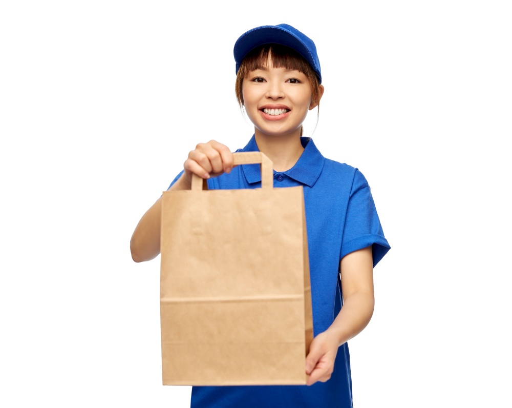 service and job concept - happy smiling delivery woman in blue uniform with takeaway food in paper bag over white background. delivery woman with takeaway food in paper bag