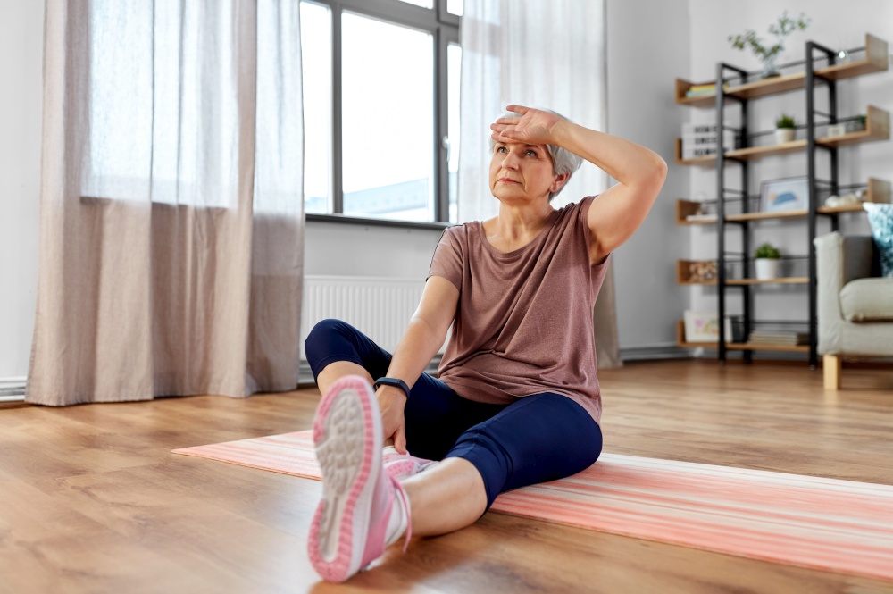 sport, fitness and healthy lifestyle concept - tired senior woman exercising on mat at home. tired senior woman exercising on mat at home