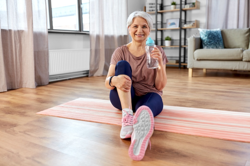 sport, fitness and healthy lifestyle concept - smiling senior woman exercising on mat at home. smiling senior woman exercising on mat at home