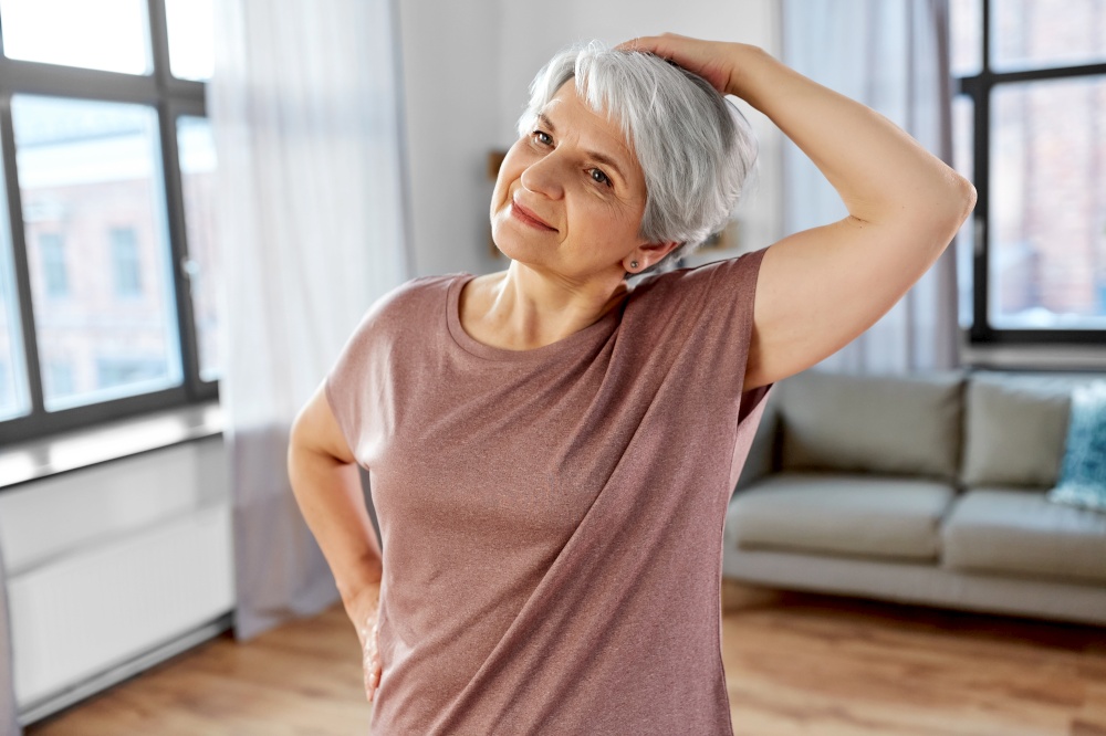 sport, fitness and healthy lifestyle concept - close up of smiling senior woman exercising on mat and stretching neck at home. close up of senior woman exercising at home