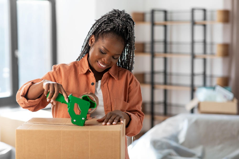 moving, people and real estate concept - happy smiling woman with adhesive tape packing box at new home. woman with adhesive tape packing box at new home