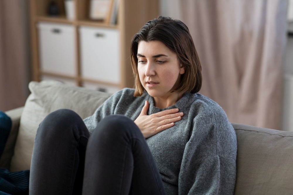 mental health, psychological problem and depression concept - sad woman having trouble breathing or panic attack at home. sad woman having panic attack at home