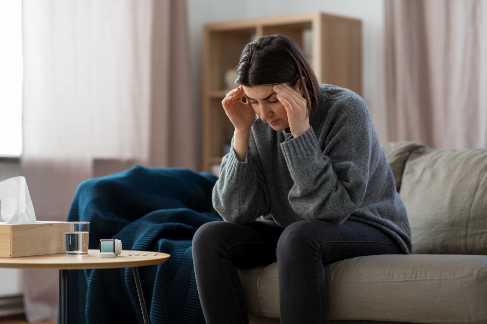 mental health, psychological problem and depression concept - stressed woman with sedative medicine or painkiller on table having headache at home. stressed woman with medicine having headache