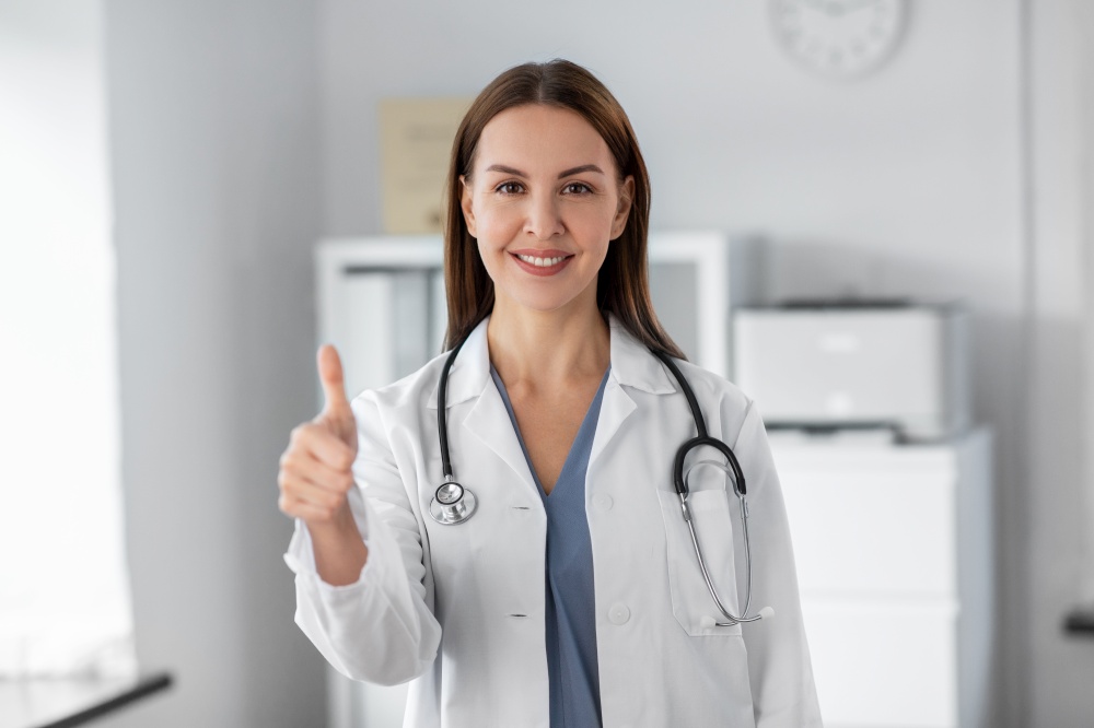 medicine, healthcare and profession concept - smiling female doctor with stethoscope showing thumbs up at hospital. happy female doctor showing thumbs up at hospital