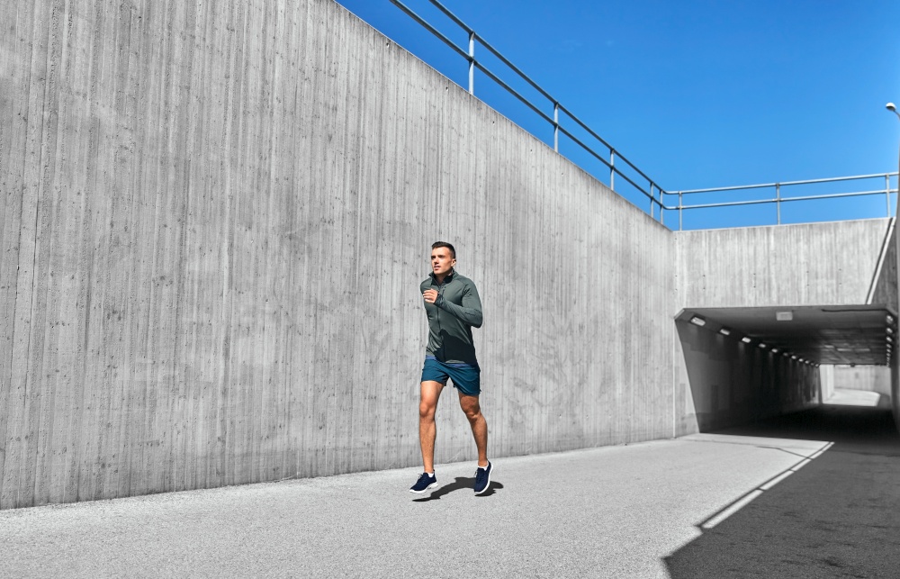 fitness, sport and healthy lifestyle concept - young man running out of tunnel. young man running out of tunnel