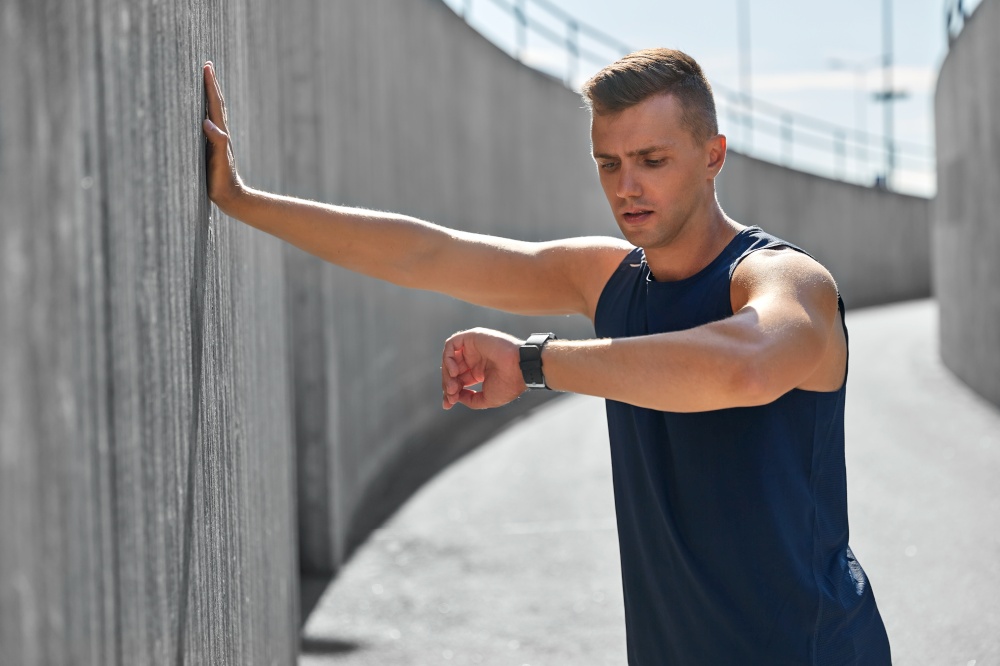 sport, technology and healthy lifestyle concept - young man with fitness tracker on city street. young man with fitness tracker on city street