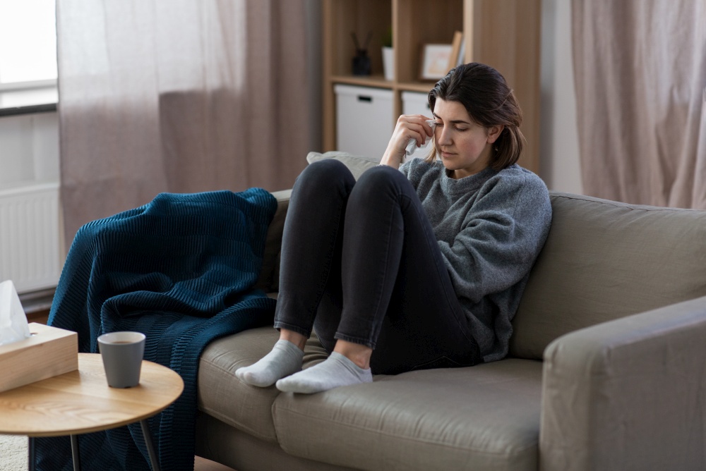 mental health, psychological problem and depression concept - sad crying woman sitting on sofa at home. sad crying woman sitting on sofa at home