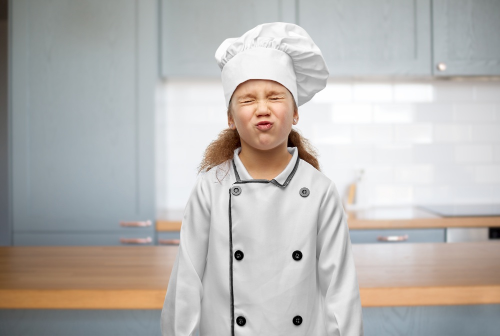 cooking, culinary and profession concept - little girl in chef&rsquo;s toque and jacket over kitchen background. little girl in chef&rsquo;s toque and jacket