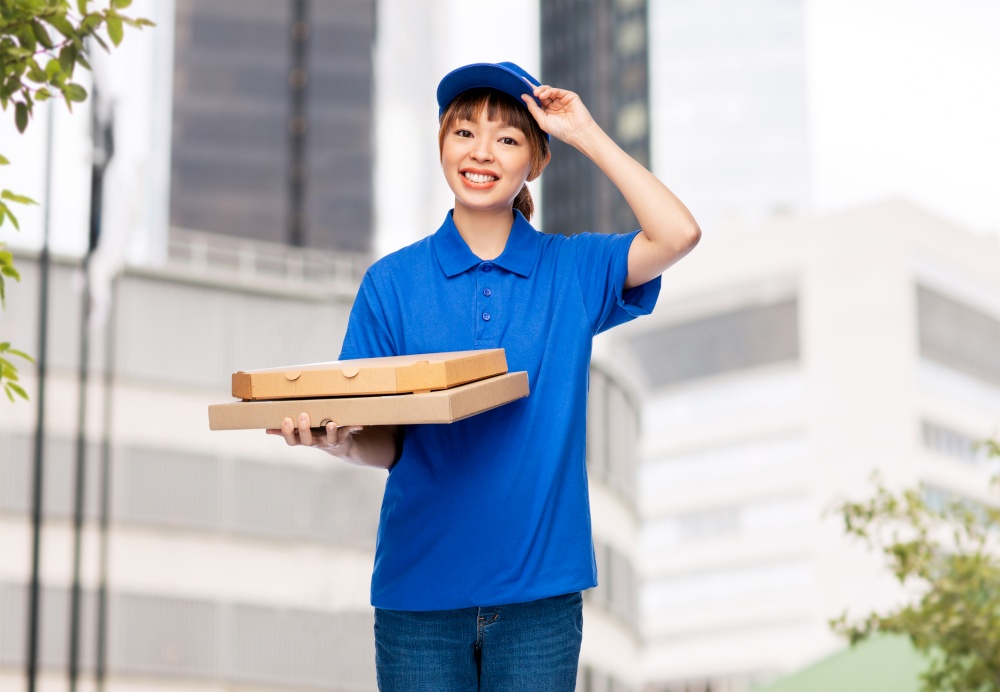food, service and job concept - happy smiling delivery woman in blue uniform with takeaway pizza boxes over city street background. delivery woman with takeaway pizza boxes in city