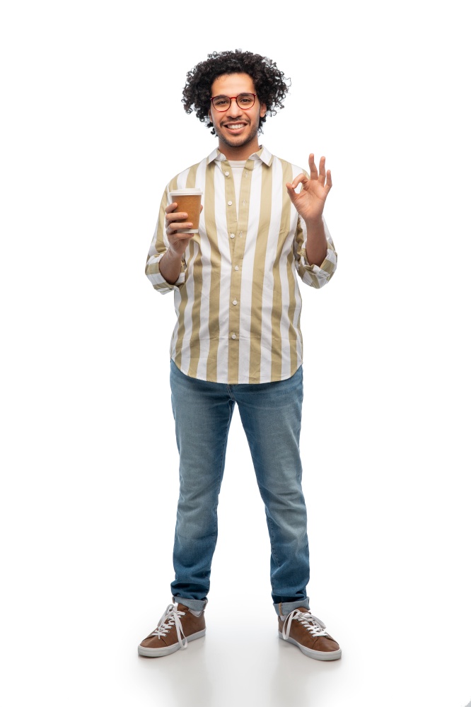 drinks and people concept - smiling young man in glasses with takeaway coffee cup showing ok gesture over white background. smiling man with coffee cup showing ok gesture