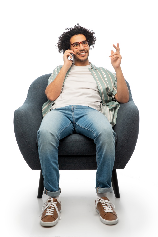 people and furniture concept - happy smiling young man in glasses sitting in chair and calling on smartphone over white background. smiling man sitting in chair calling on smartphone
