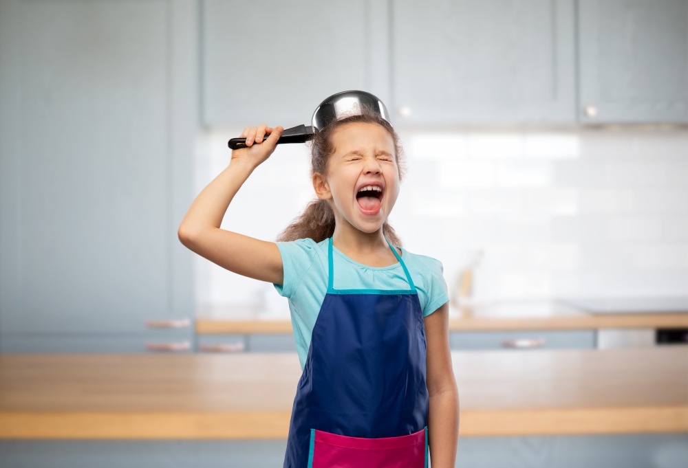cooking, culinary and profession concept - happy smiling little girl in apron playing with saucepan over home kitchen background. happy little girl in apron playing with saucepan