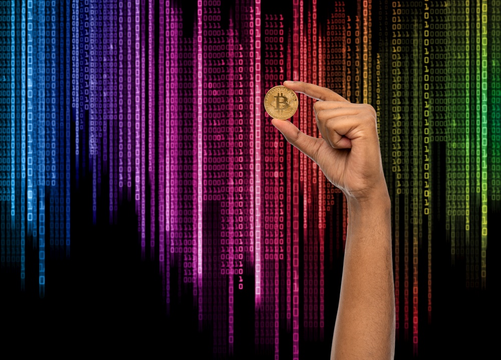 cryptocurrency, finance and business concept - close up of female hand holding golden bitcoin over binary code background. close up of hand with bitcoin over binary code
