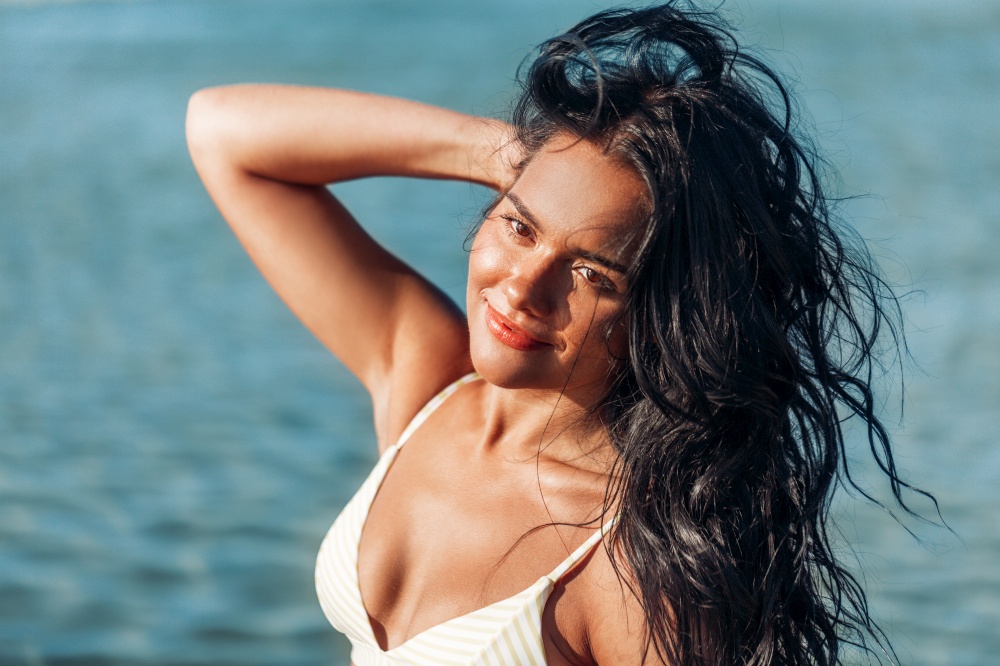 people, summer and leisure concept - happy smiling young woman in bikini swimsuit on beach. smiling young woman in bikini swimsuit on beach