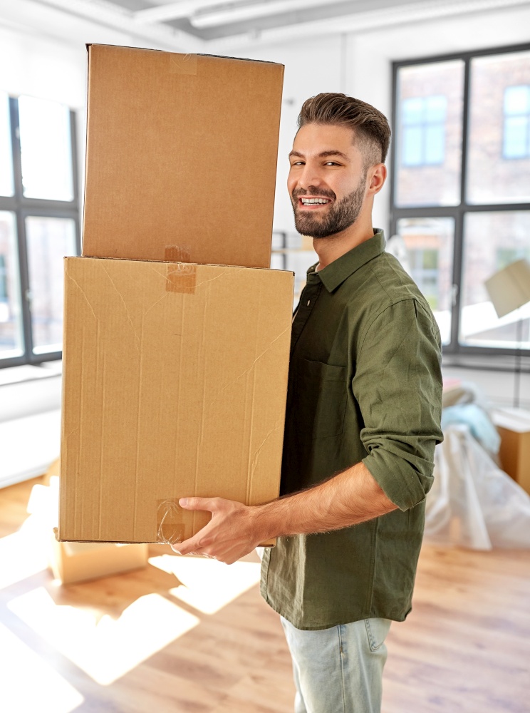moving, people and real estate concept - happy smiling man holding boxes with stuff at new home. happy man with boxes moving to new home